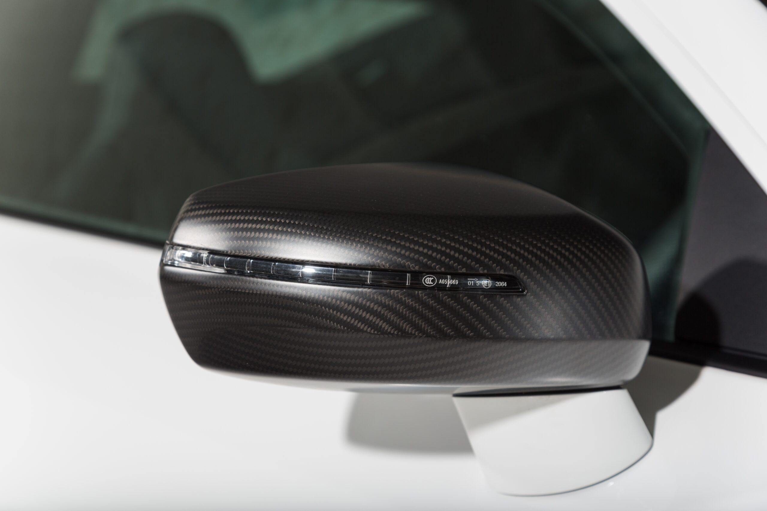A closeup shot of the black side mirror of a modern white car